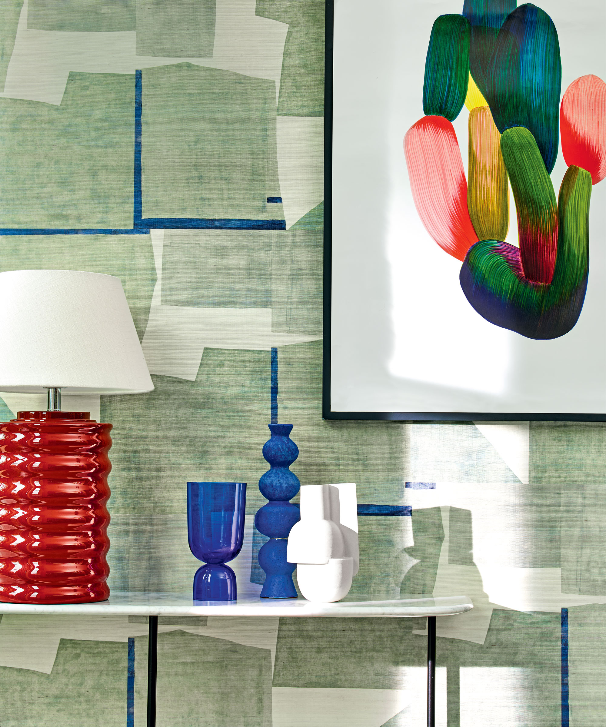 Entrada colorida con papel pintado abstracto verde, obras de arte enmarcadas, estante blanco, lámpara de mesa roja, adornos decorativos