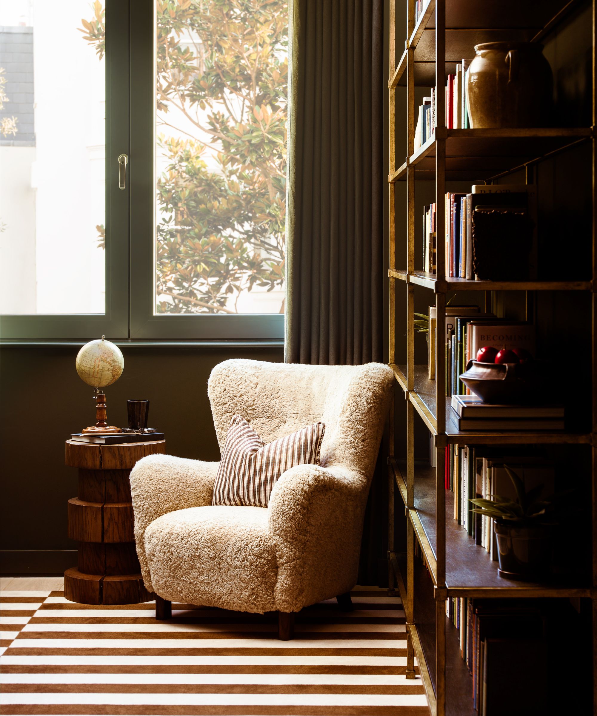 Una silla de bouclé blanca en la esquina de una biblioteca doméstica