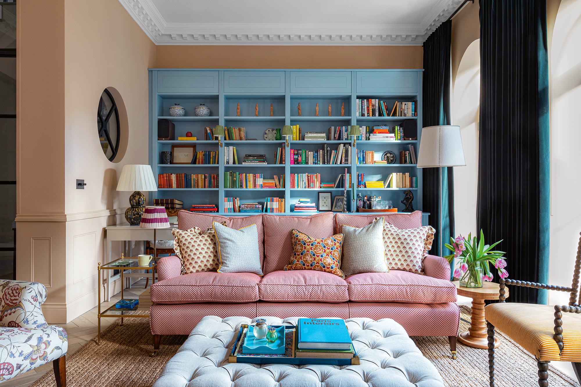 sala de estar con una estantería azul a medida y un sofá rosa y paredes color crema