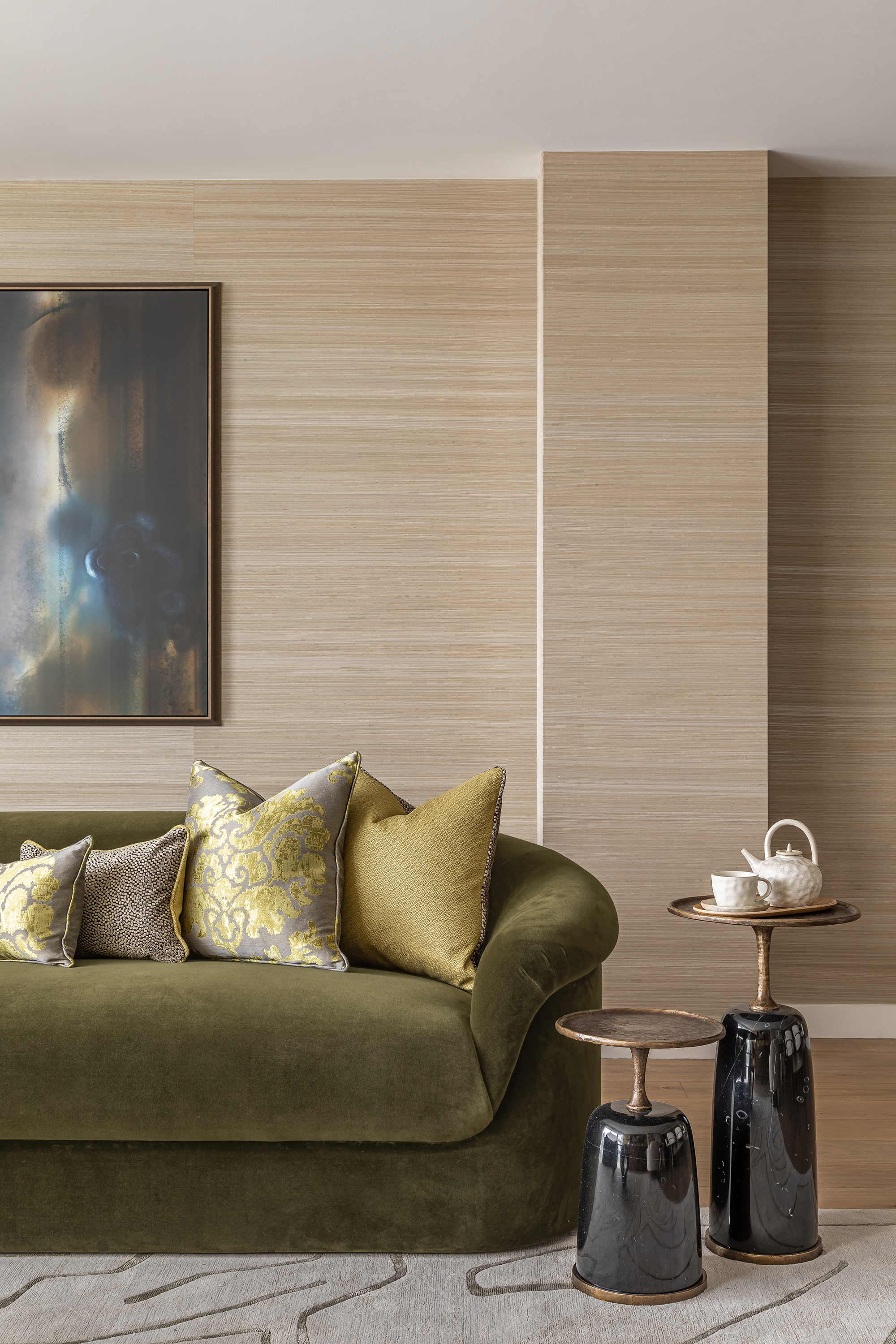 sala de estar neutra con paredes de madera y sofá de terciopelo en verde musgo con cojines y mesas de acento verde