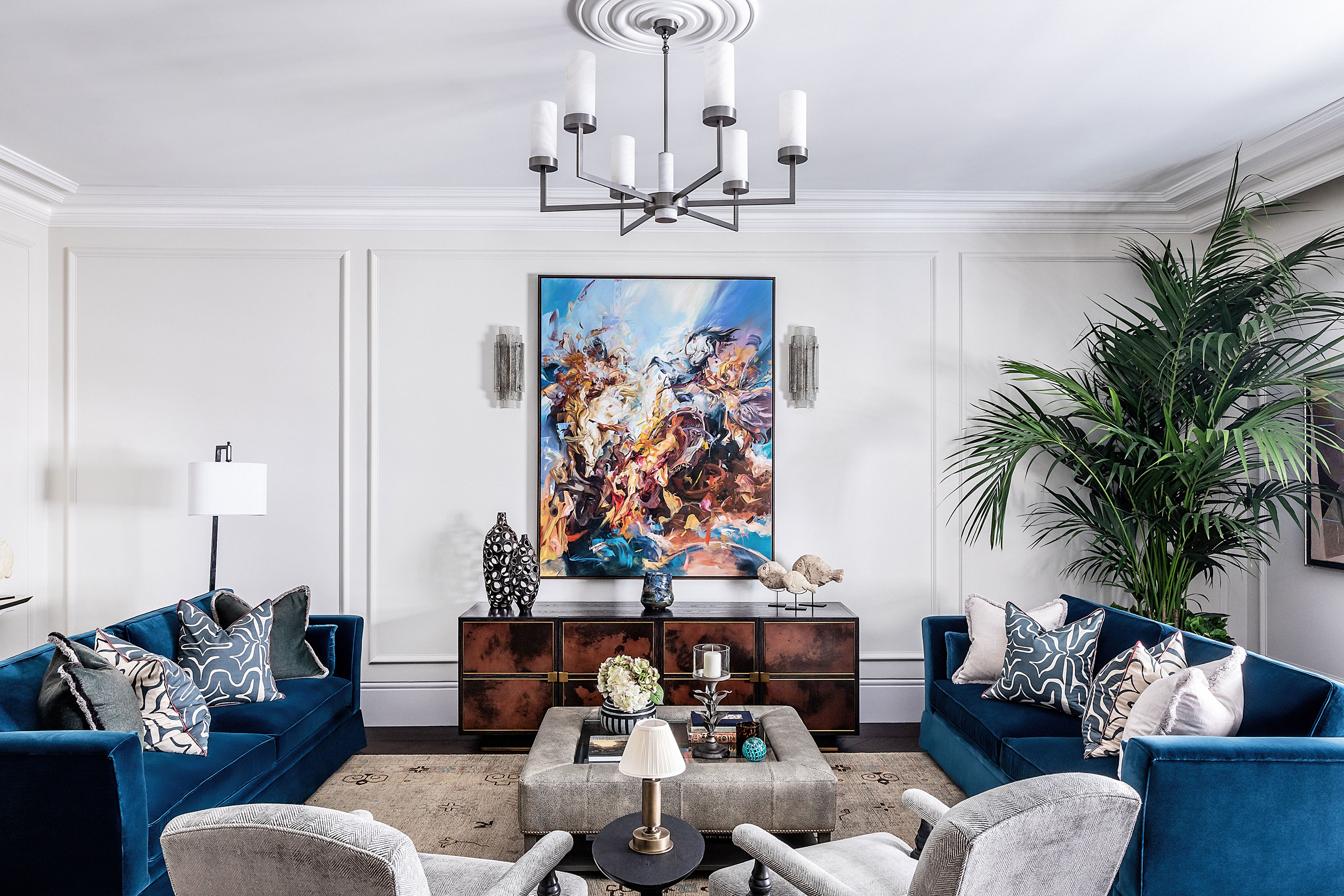 sala de estar con sofás azules y sillas grises y obras de arte modernas