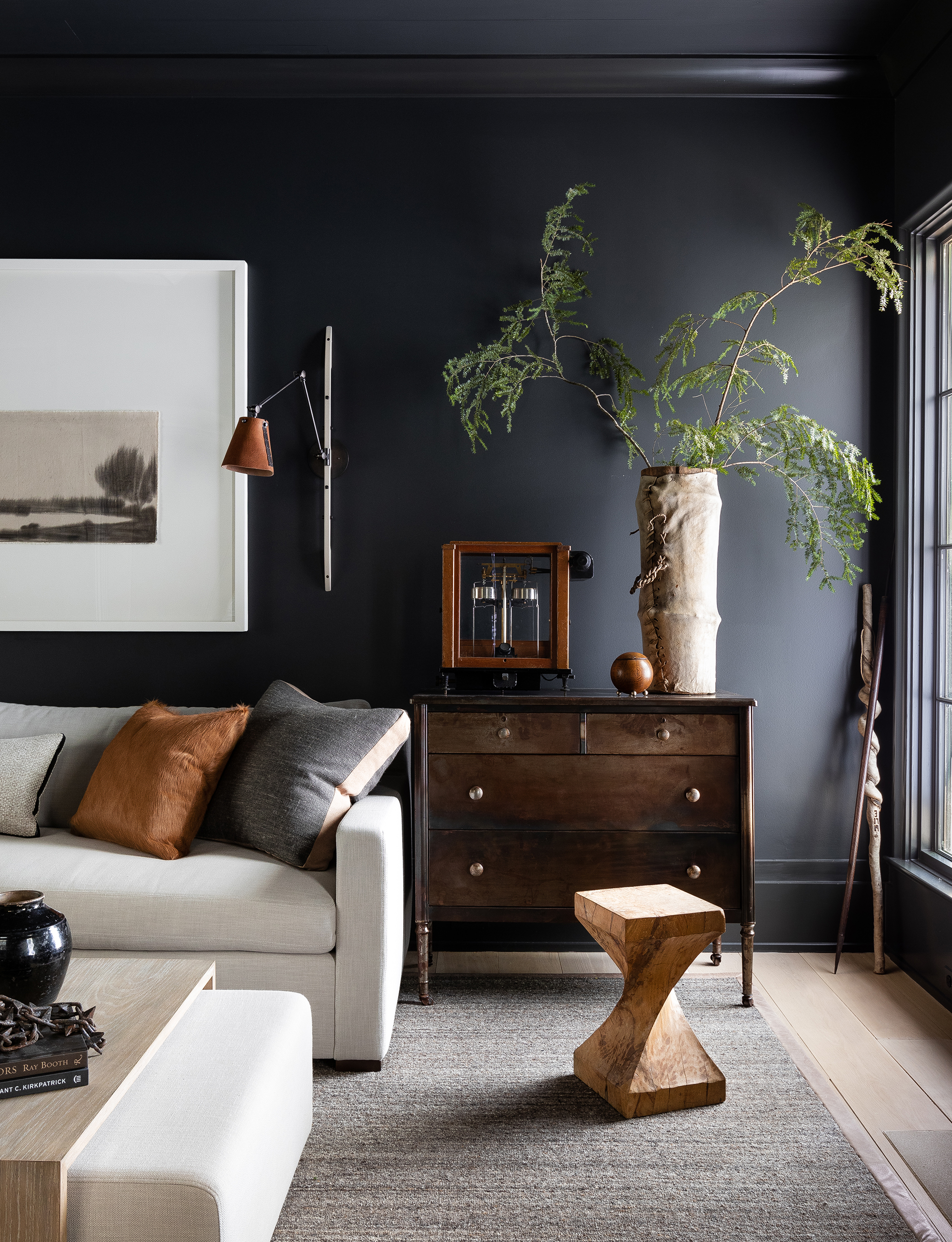 Salón negro con sofá blanco y materiales naturales.