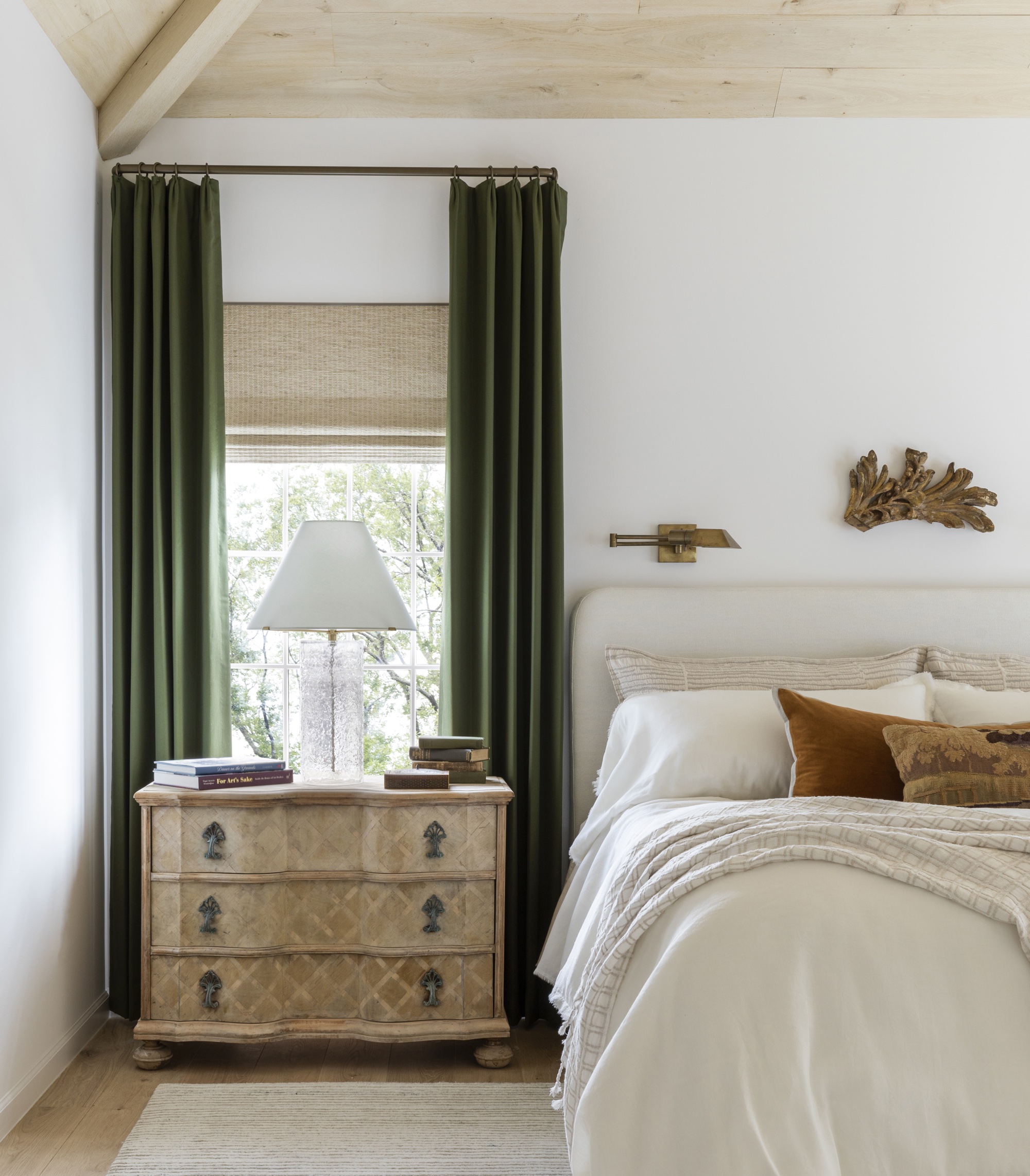 dormitorio blanco con cortinas verdes y mesita de noche de madera de Marie Flanigan
