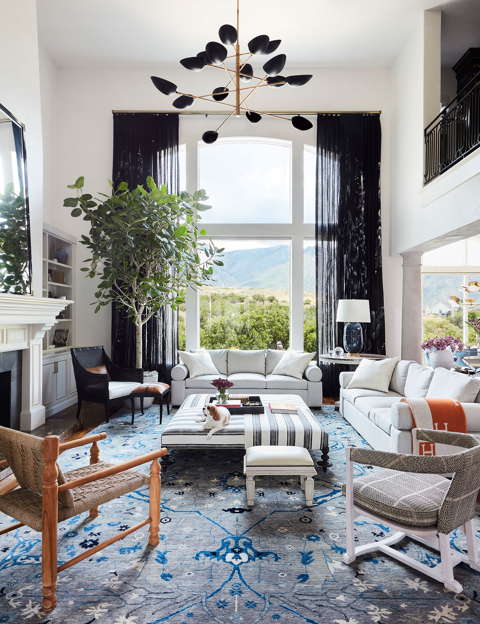 Sala de estar moderna con dos sofás, cortinas negras y alfombra azul.