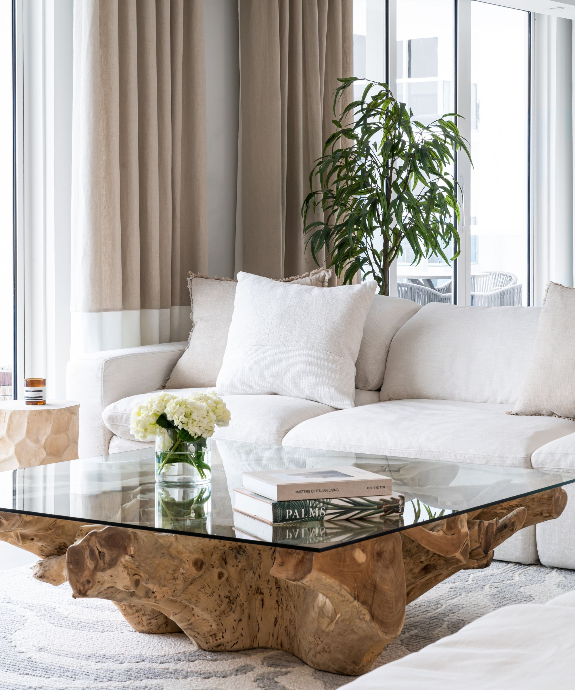 Un sofá blanco con una mesa de vidrio con base de madera.