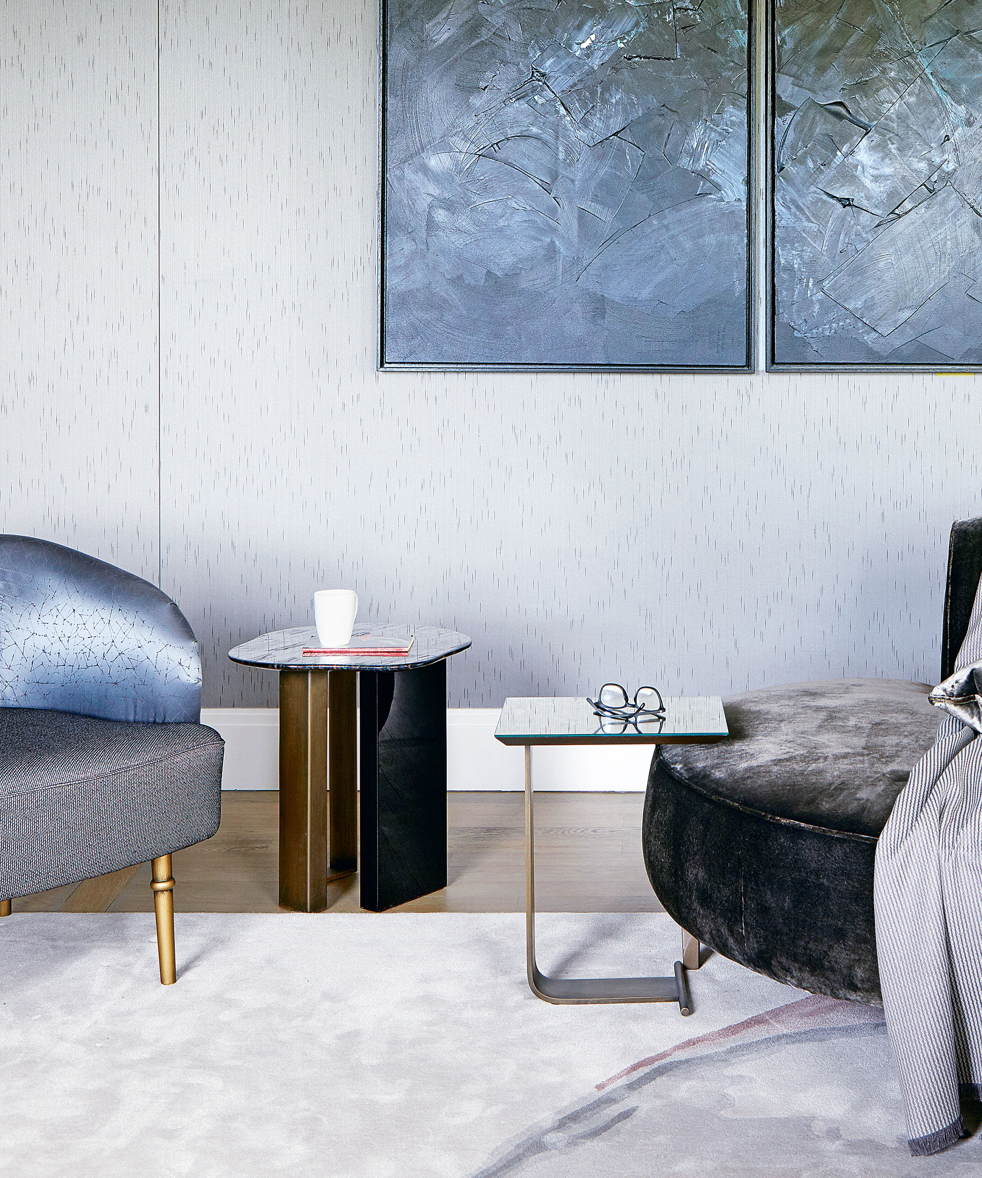 Sala de estar moderna con dos elegantes mesas auxiliares, grandes obras de arte en la pared y un sillón de terciopelo azul