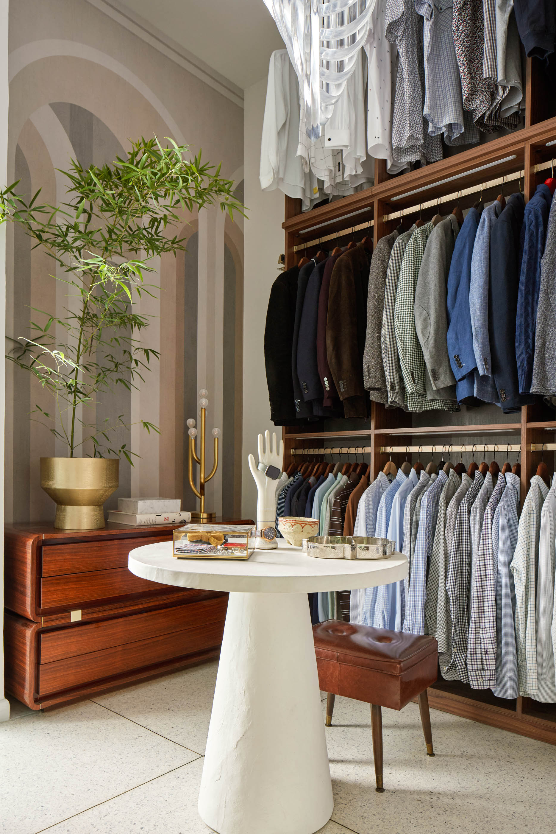 armario con almacenamiento abierto para colgar camisas y chaquetas, mesa redonda para joyas, cómoda, macetero dorado y planta